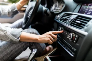 Mulher ajusta o dial do rádio no carro, ilustrando a importância da frequência no rádio e do planejamento de campanhas publicitárias para alcançar melhores resultados.